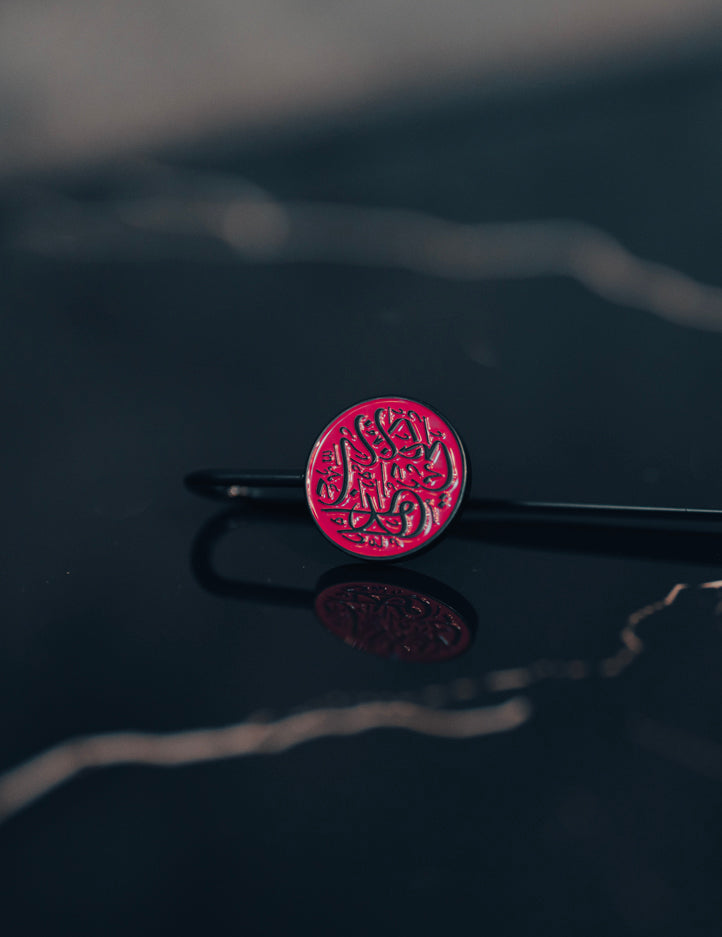 Amaani Quraan Marker lying flat, pink calligraphy crest on a matt black metal spine